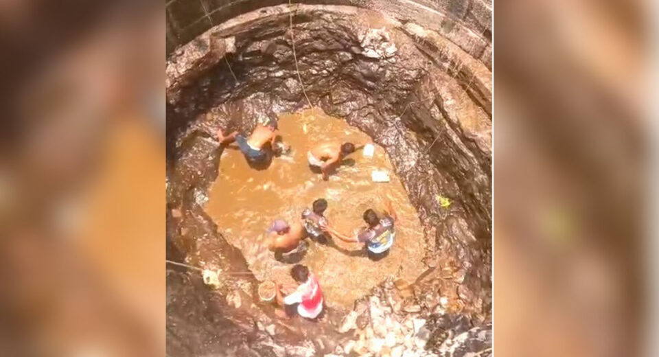 Villagers standing inside a nearly dry well collecting muddy water in Barvi dam affected villages Murbad Maharashtra