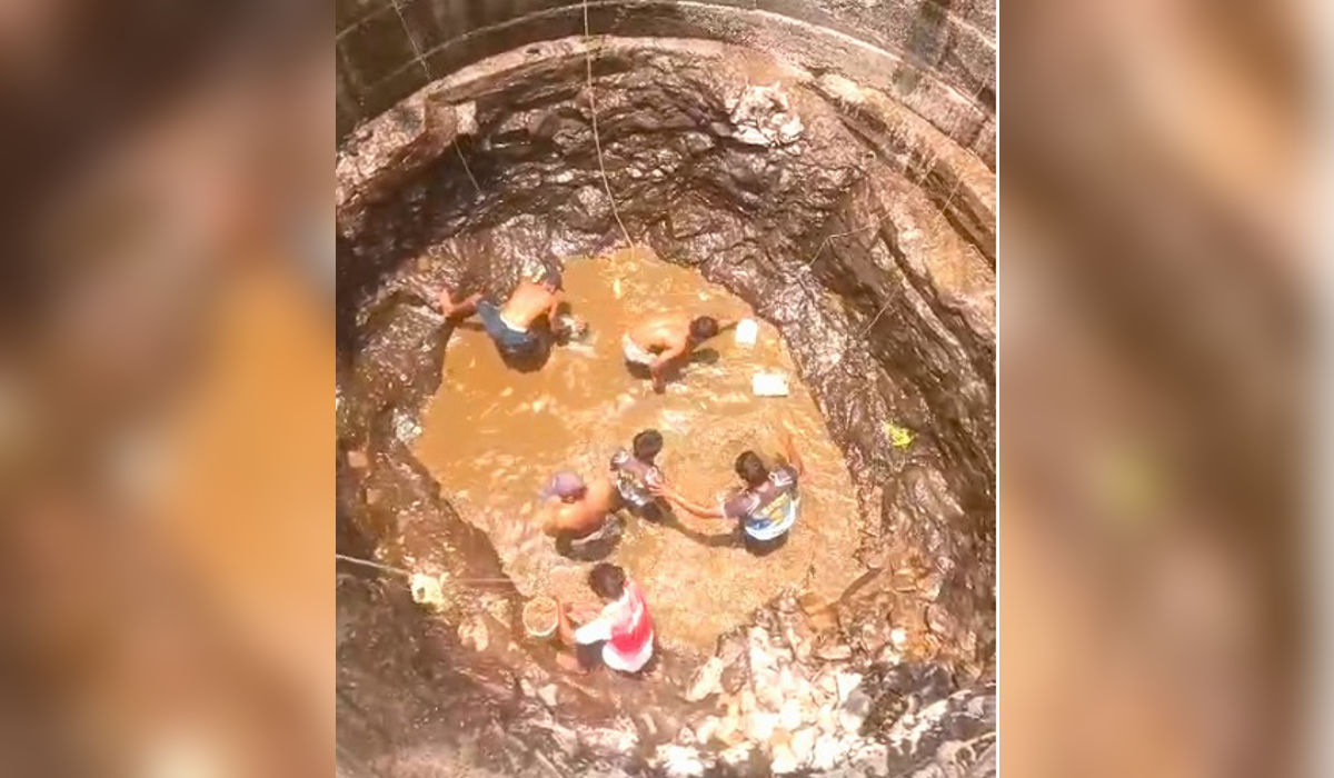 Villagers standing inside a nearly dry well collecting muddy water in Barvi dam affected villages Murbad Maharashtra