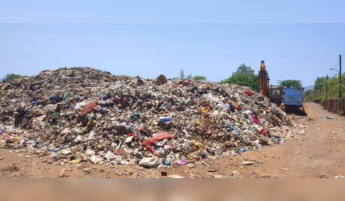 Massive garbage pile at Ladvali dumping ground in Mahad, Raigad, with an excavator machine highlighting poor waste management conditions