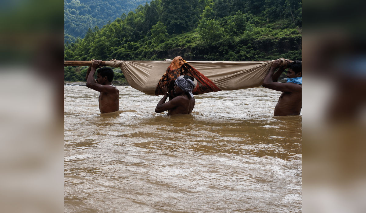 दुर्गम आदिवासी भागात बांबूच्या डोल्यातून नदी ओलांडून रुग्णाला उपचारासाठी नेताना ग्रामस्थ.