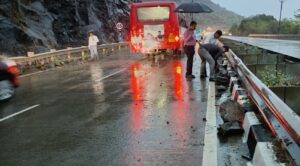 Large rocks and debris scattered on the Mumbai-Goa National Highway near Kemburli in Mahad after a landslide during heavy rain, with vehicles halted and commuters assessing the damage.