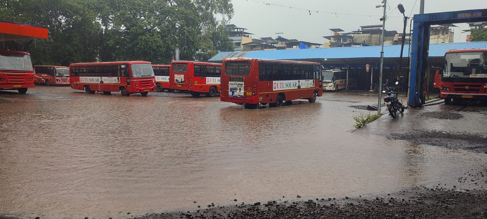Multiple Maharashtra State Transport (ST) buses parked in floodwater at Mahad Bus Stand after heavy monsoon rain in Raigad district.