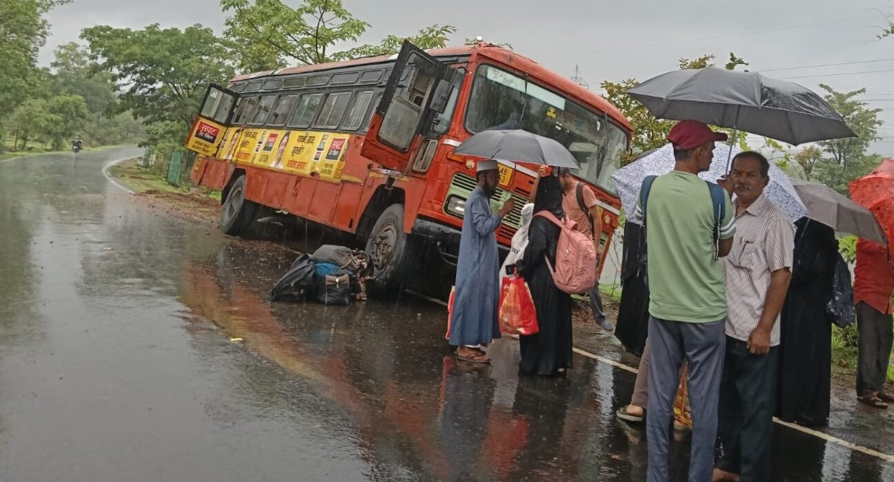 Maharashtra State Transport (ST) bus tilted off the Mahad-Dapoli State Highway near Kurle village after skidding on a rain-soaked road, while passengers stand safely outside.