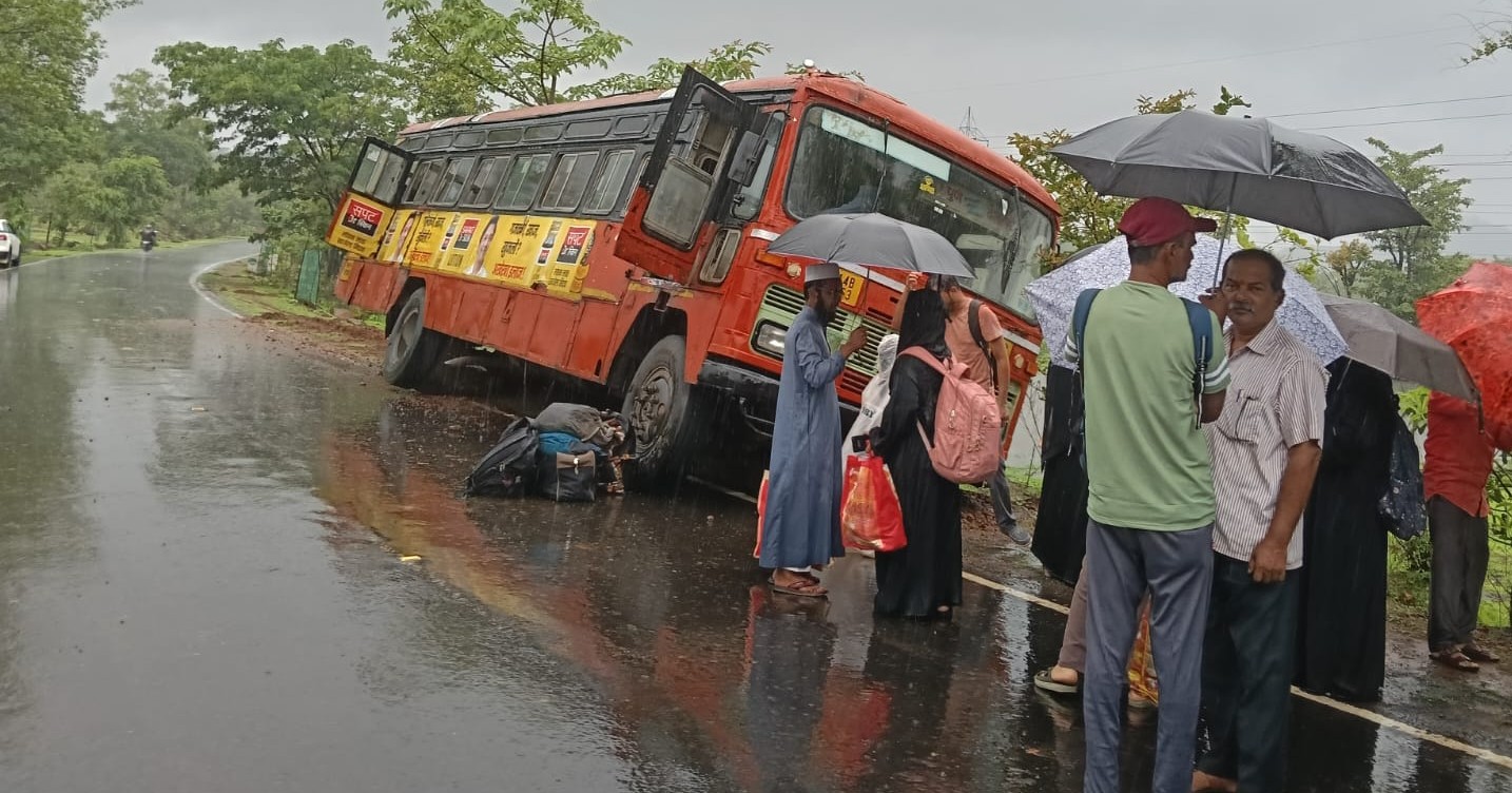 Maharashtra State Transport (ST) bus tilted off the Mahad-Dapoli State Highway near Kurle village after skidding on a rain-soaked road, while passengers stand safely outside.
